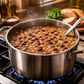 Stovetop with a pot of beans simmering, surrounded by bread and herbs.